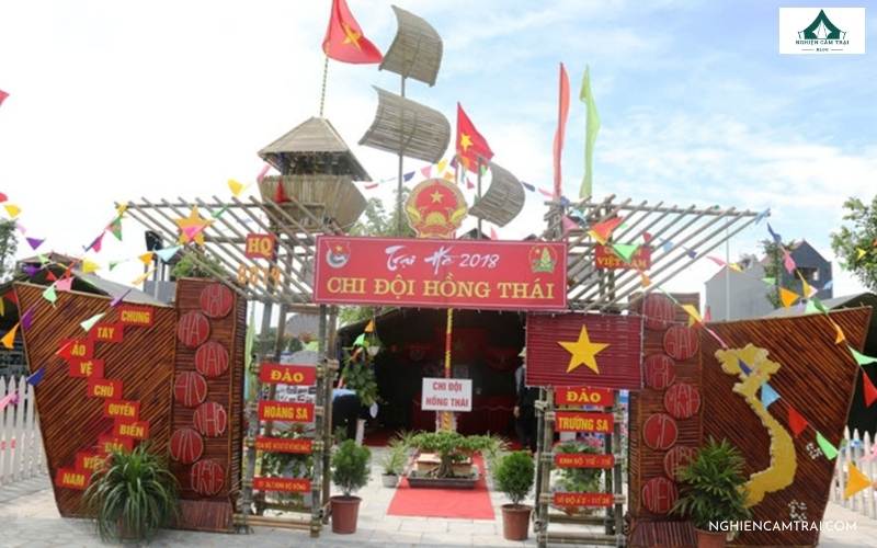 Trang trí cổng trại theo chủ đề đã chọn với cờ, hoa và dây ruy băng